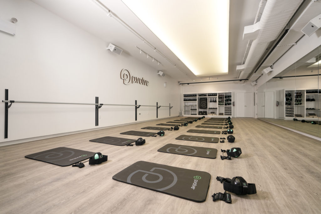Pvolve gym with yoga mats and other accessories lined up and ready to be used by a group of people.