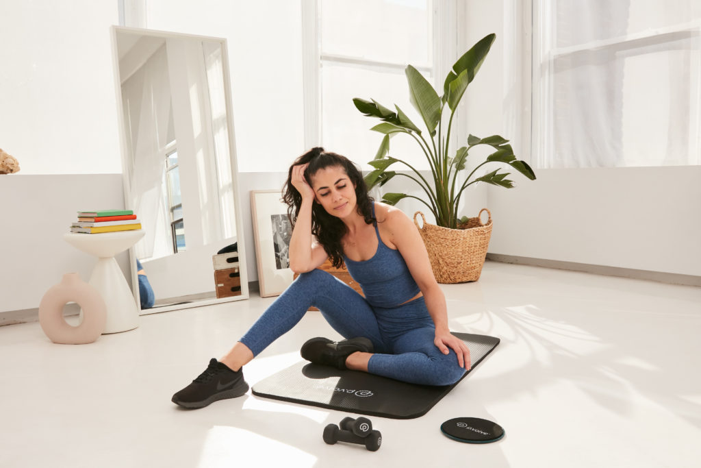 Content woman sitting on P.volve mat with legs bent and relaxed
