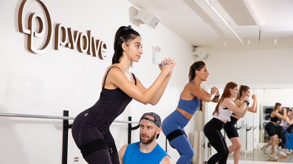 Image of a group of women working out at a P.volve studio with a male instructor.
